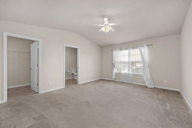 178 E Iron Horse Dr, Crestview, FL 32539 - unfurnished bedroom with a walk in closet, light colored carpet, vaulted ceiling, and baseboards