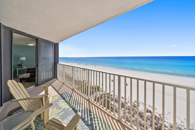 balcony with a water view and a view of the beach