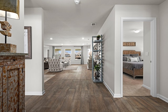 hall with dark wood-style floors, visible vents, and baseboards