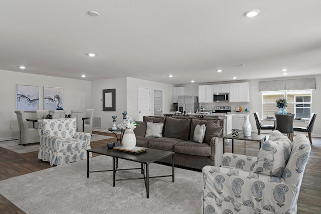 living area with baseboards, wood finished floors, visible vents, and recessed lighting