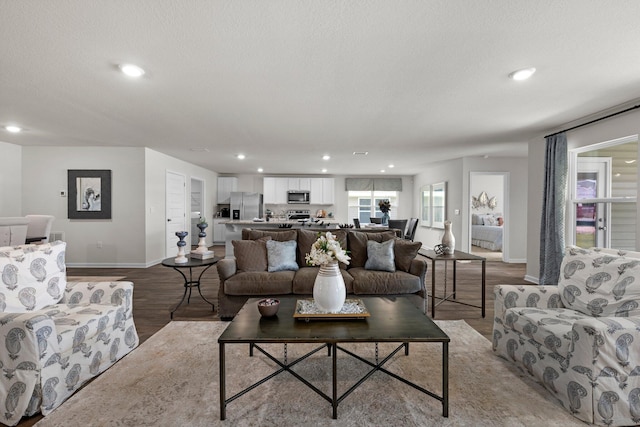 living area with a textured ceiling, baseboards, light wood-style flooring, and recessed lighting