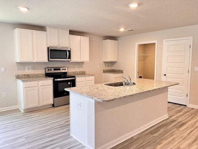 kitchen with white cabinets, a kitchen island with sink, stainless steel appliances, and a sink