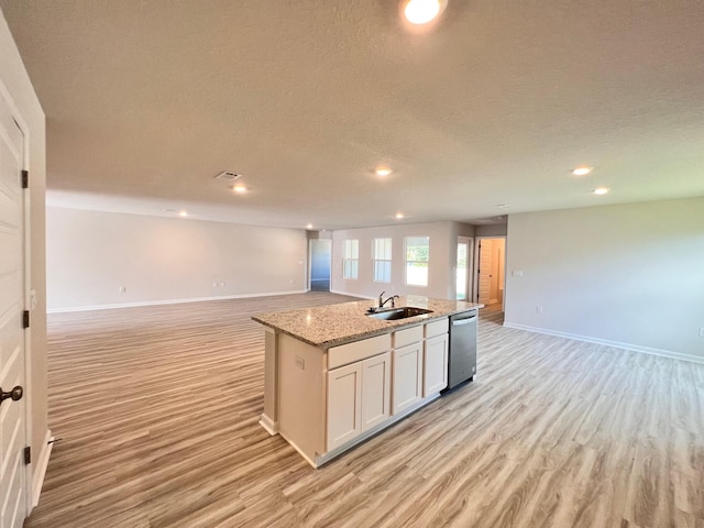 kitchen featuring light wood-style floors, open floor plan, white cabinetry, a sink, and an island with sink