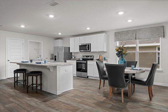 kitchen with stainless steel appliances, an island with sink, visible vents, and white cabinets