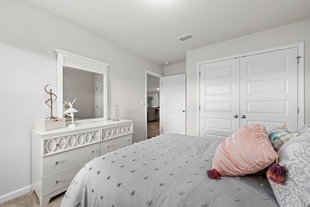 bedroom featuring a closet, carpet flooring, visible vents, and baseboards