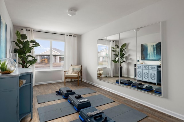 workout area featuring baseboards and dark wood finished floors