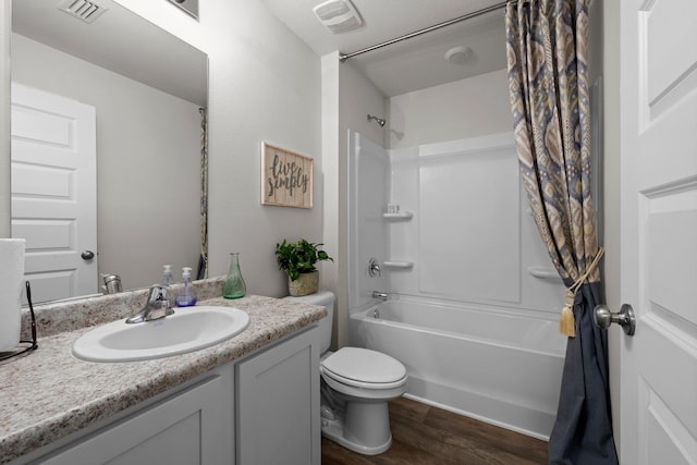 full bathroom with vanity, shower / bath combo, wood finished floors, and visible vents