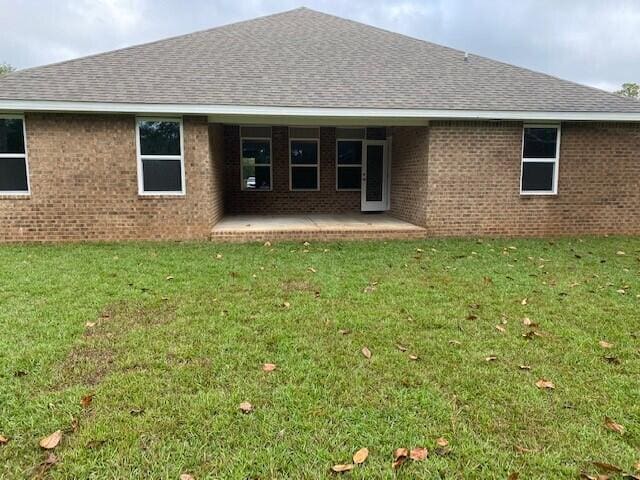 back of property with brick siding, a yard, and a patio