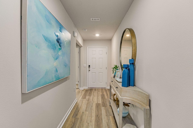 hallway with light wood-type flooring, baseboards, and visible vents