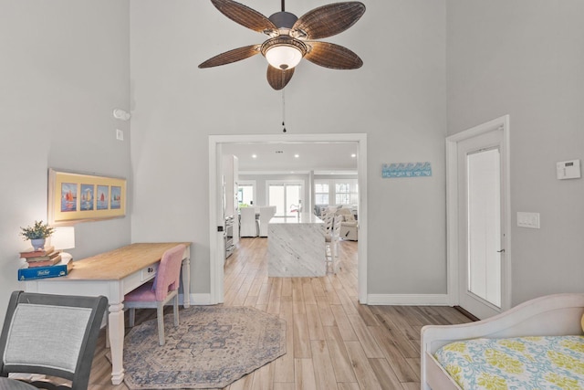 bedroom with a high ceiling, baseboards, and light wood finished floors