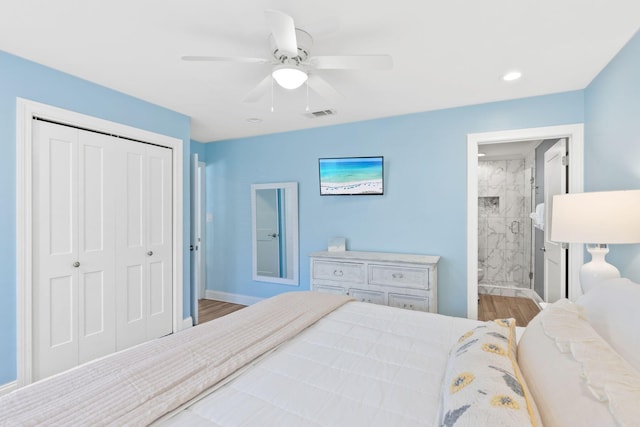 bedroom featuring wood finished floors, baseboards, ceiling fan, a closet, and ensuite bathroom