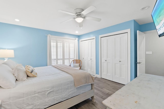 bedroom featuring recessed lighting, ceiling fan, multiple closets, and wood finished floors