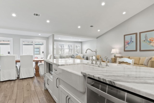 kitchen featuring light stone counters, light wood-style floors, dishwasher, and open floor plan