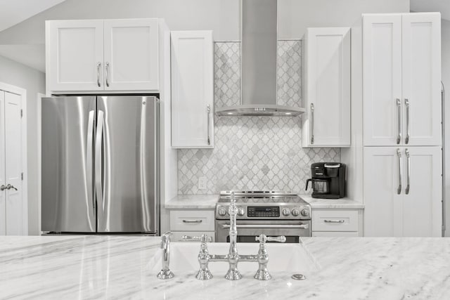 kitchen featuring wall chimney range hood, white cabinets, backsplash, and stainless steel appliances