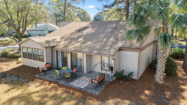 rear view of property featuring a shingled roof and a patio area