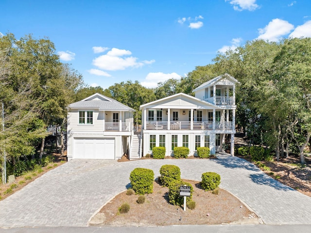 view of front facade featuring decorative driveway, a balcony, an attached garage, and stairs