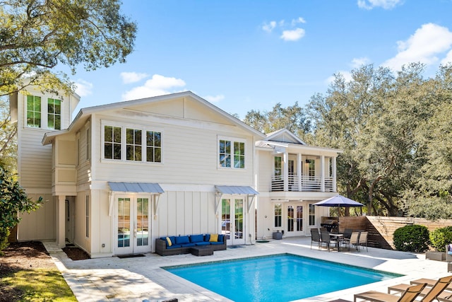 rear view of house featuring a patio, an outdoor hangout area, fence, french doors, and board and batten siding