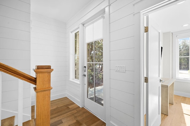 doorway to outside featuring wooden walls, light wood-style flooring, and baseboards