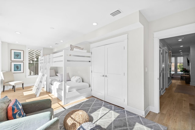 bedroom with baseboards, visible vents, wood finished floors, a closet, and recessed lighting