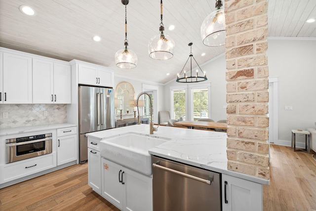 kitchen with stainless steel appliances, a kitchen island with sink, white cabinetry, and decorative light fixtures