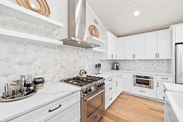 kitchen with stainless steel appliances, white cabinets, wall chimney exhaust hood, and open shelves