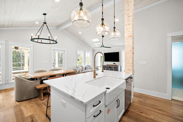 kitchen featuring decorative light fixtures, a center island with sink, light wood finished floors, open floor plan, and white cabinets