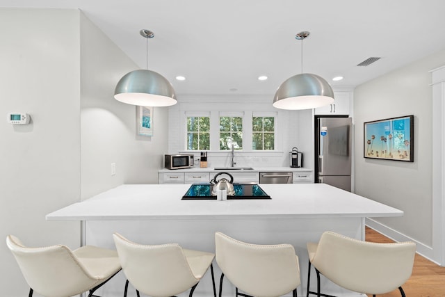 kitchen with visible vents, white cabinetry, stainless steel appliances, and light countertops