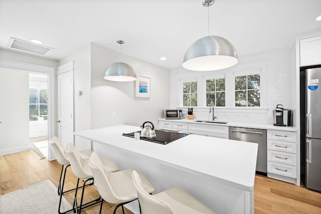 kitchen featuring visible vents, white cabinets, light countertops, appliances with stainless steel finishes, and decorative light fixtures