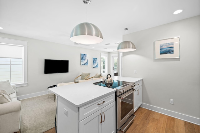 kitchen featuring white cabinetry, open floor plan, electric stove, hanging light fixtures, and light countertops