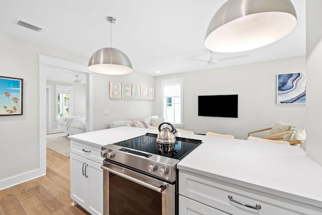 kitchen featuring open floor plan, light countertops, electric range, and white cabinets