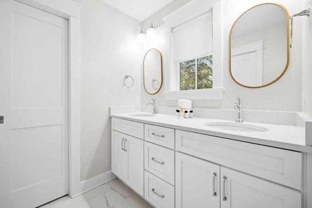 bathroom featuring double vanity, marble finish floor, baseboards, and a sink