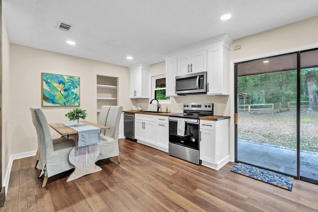 5241 Bob Sikes Rd, Defuniak Springs, FL 32435 - kitchen with appliances with stainless steel finishes, a sink, wood finished floors, white cabinetry, and recessed lighting