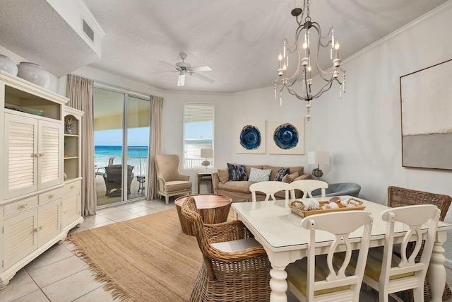 dining space featuring light tile patterned floors, a textured ceiling, ceiling fan with notable chandelier, a water view, and visible vents