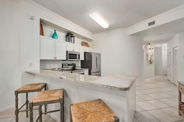 kitchen with a peninsula, appliances with stainless steel finishes, visible vents, and crown molding