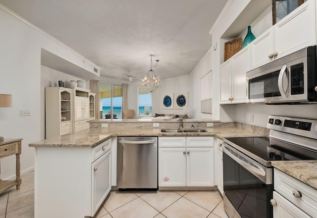 kitchen with light tile patterned flooring, a peninsula, a sink, white cabinetry, and appliances with stainless steel finishes