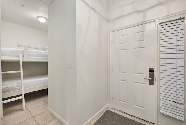 entryway with light tile patterned floors, baseboards, and a textured ceiling