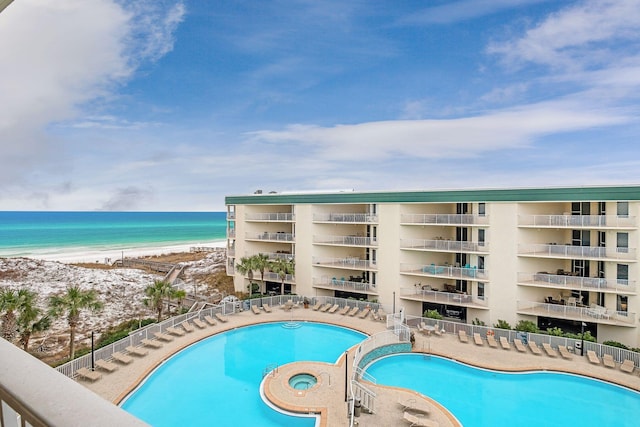 pool with a water view, a community hot tub, and a view of the beach