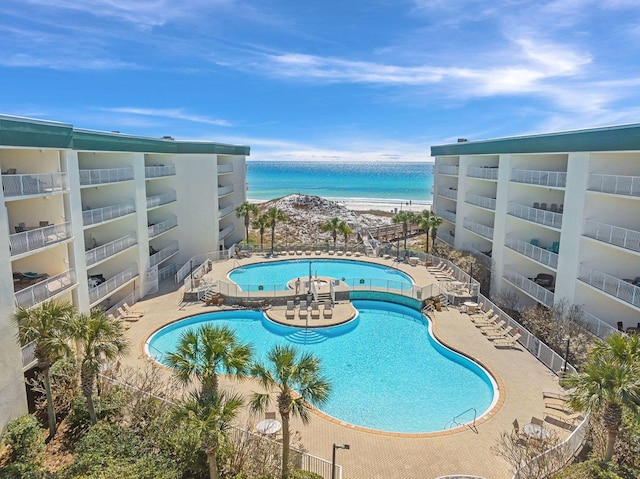 pool featuring a patio, a water view, and a view of the beach