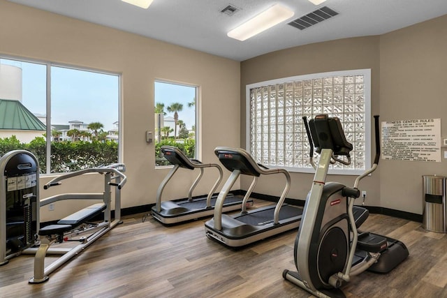 workout area featuring visible vents, baseboards, and wood finished floors