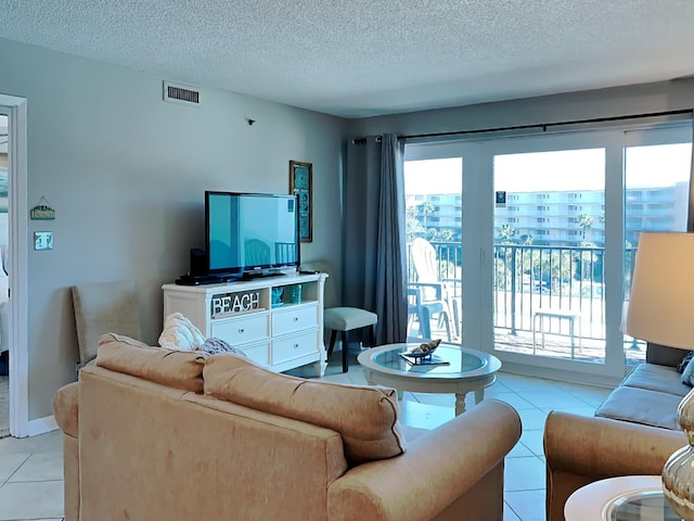 living room featuring light tile patterned floors, a textured ceiling, visible vents, and baseboards