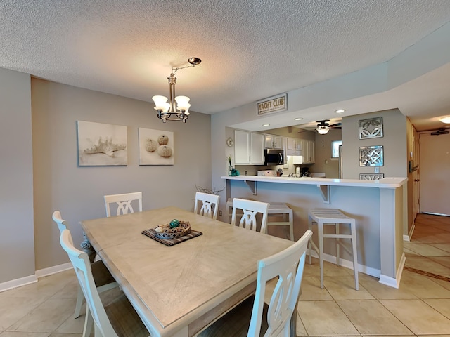 dining area featuring light tile patterned floors, baseboards, and ceiling fan with notable chandelier