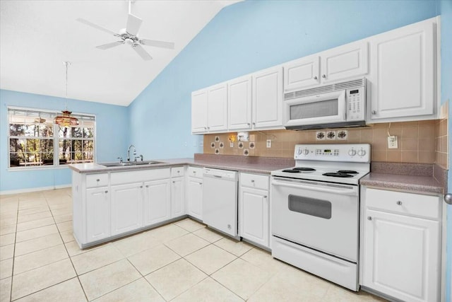 kitchen with light tile patterned floors, a peninsula, white appliances, a sink, and white cabinetry