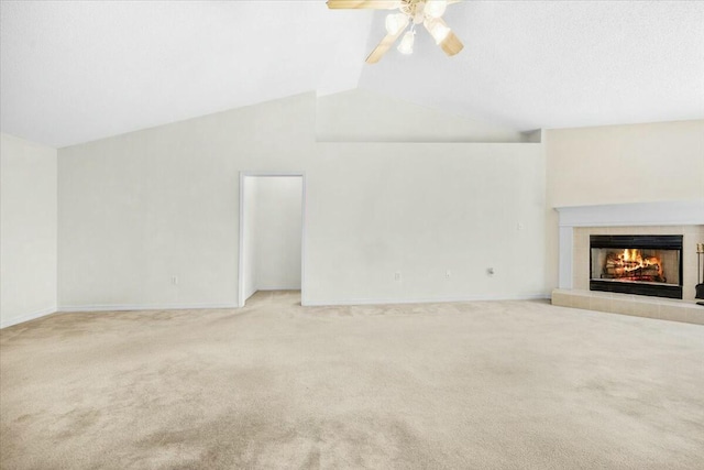 unfurnished living room with carpet floors, a tiled fireplace, vaulted ceiling, ceiling fan, and baseboards