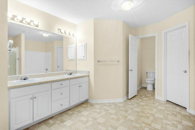 bathroom with double vanity, baseboards, and a sink