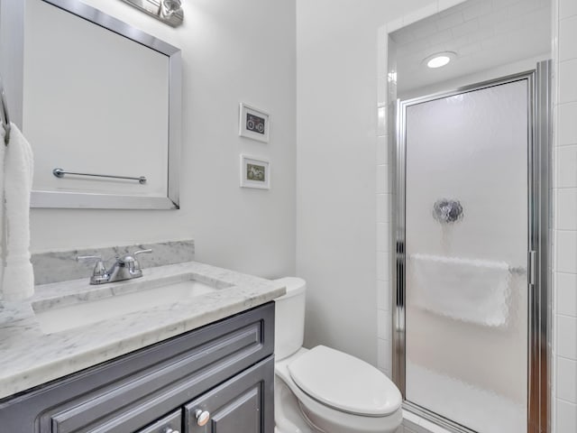 full bathroom featuring vanity, a shower stall, and toilet