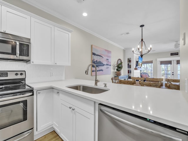 kitchen with a sink, visible vents, light countertops, ornamental molding, and appliances with stainless steel finishes