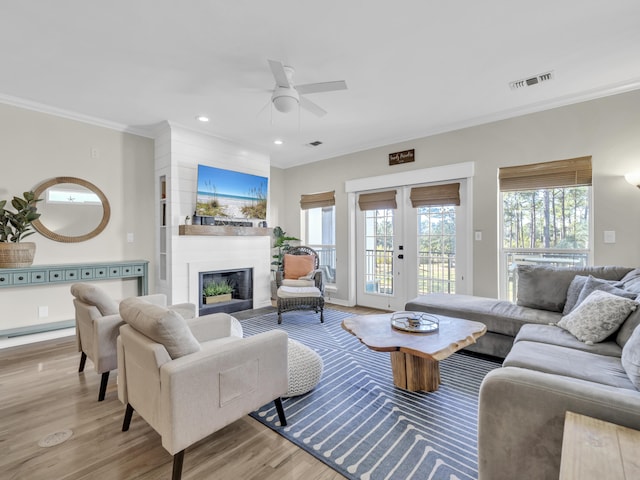 living area with visible vents, wood finished floors, crown molding, french doors, and a fireplace