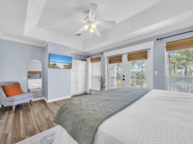 bedroom featuring wood finished floors, visible vents, baseboards, access to exterior, and a tray ceiling