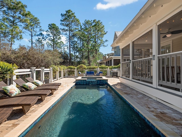 view of pool featuring a pool with connected hot tub, fence, a sunroom, ceiling fan, and a patio area