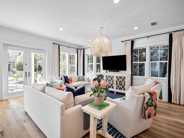 living area featuring visible vents, light wood-style flooring, recessed lighting, french doors, and an inviting chandelier